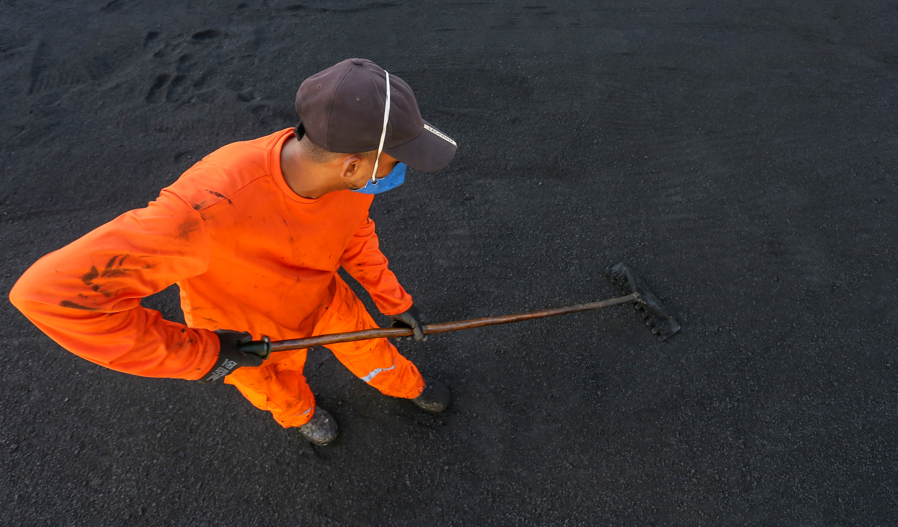 operário manuseando asfalto com pá